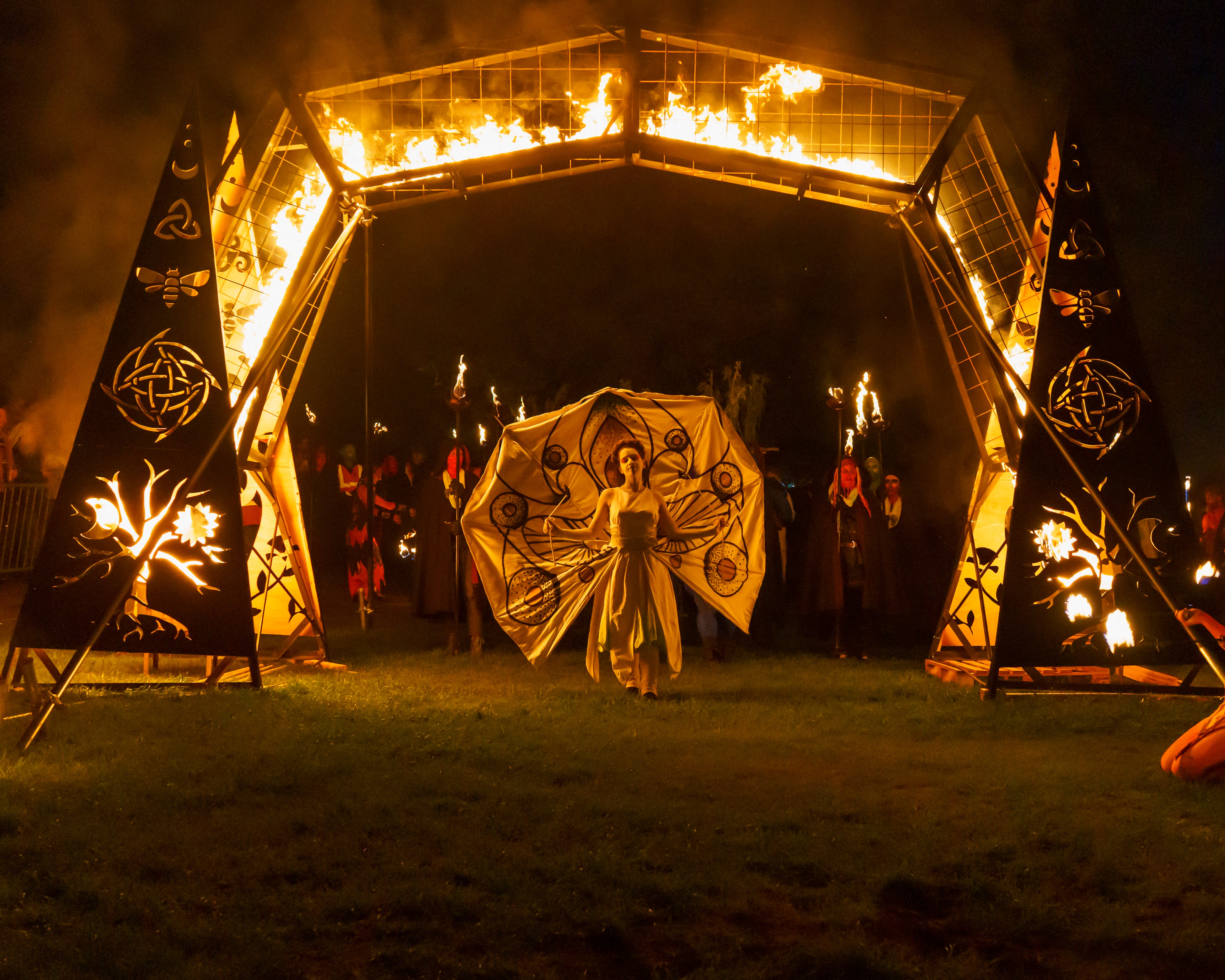 This year's winged May Queen walks through a fire arch in The Dell