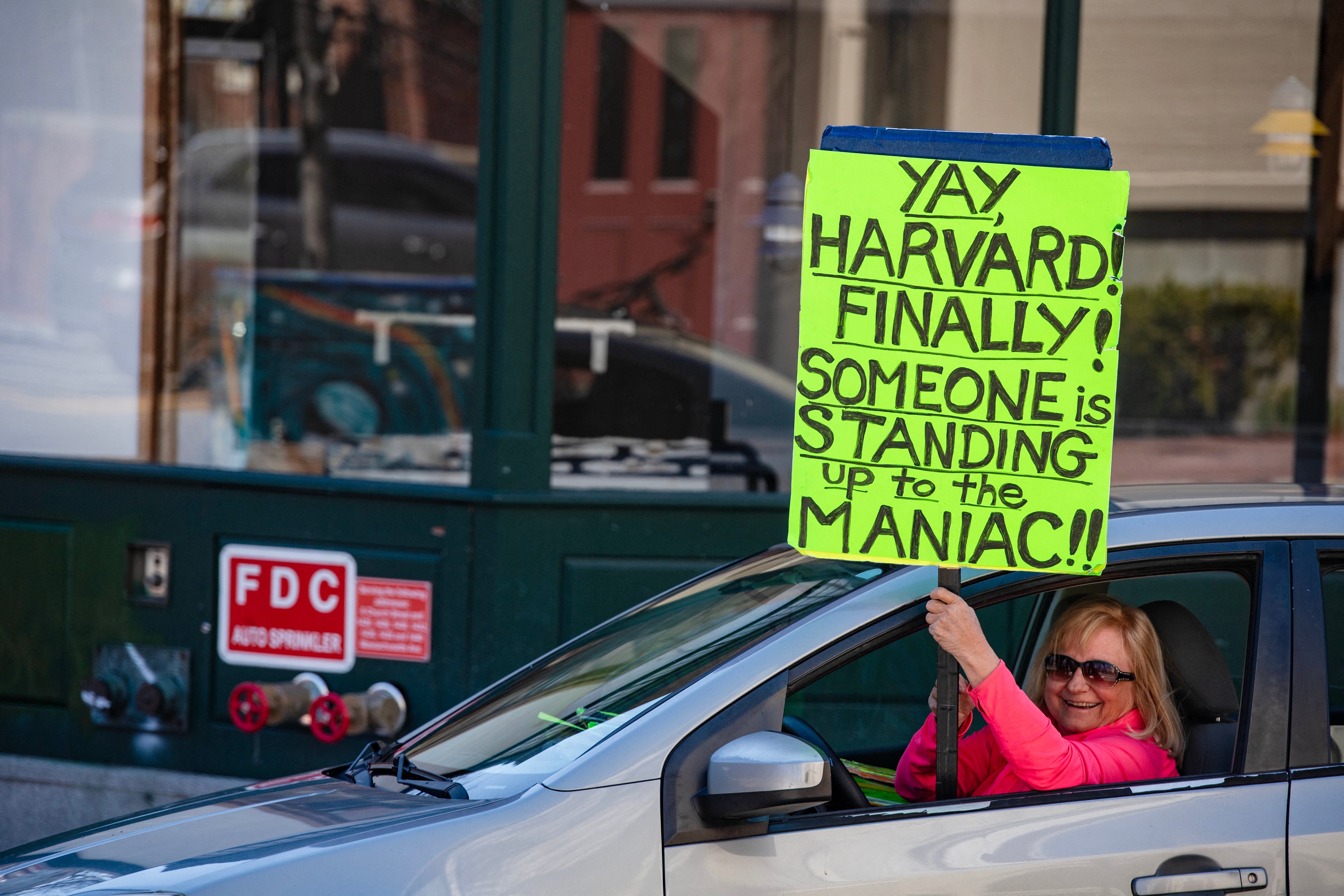 A demonstrator holds a sing in Harvard Square after a rally was held against President Donald Trump's attacks on Harvard University. The president suggested on Wednesday the university is teaching ‘remedial math’ to its students